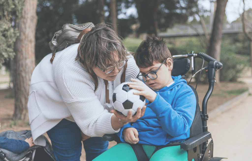 caregiver and child with medically complex needs holding a soccer ball